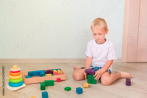 Cute little boy playing with colored wooden blocks © len44ik