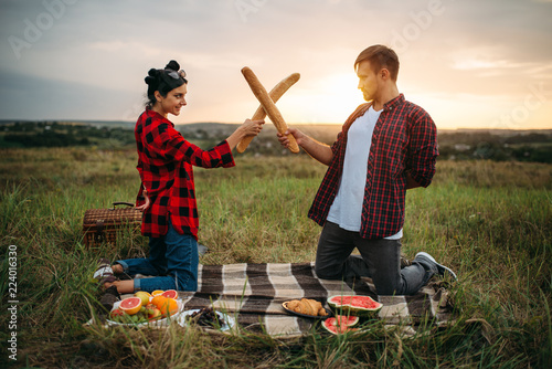Foto Playful couple fight on loaves, picnic in field