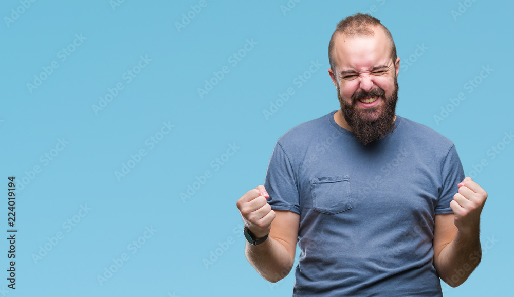 Fototapeta premium Young caucasian hipster man over isolated background very happy and excited doing winner gesture with arms raised, smiling and screaming for success. Celebration concept.