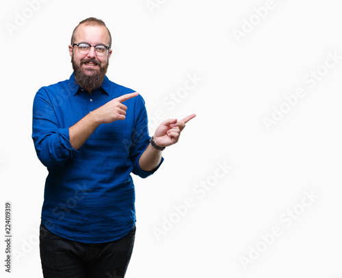 Young caucasian hipster man wearing glasses over isolated background smiling and looking at the camera pointing with two hands and fingers to the side.