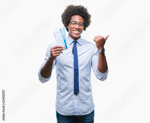 Afro american man holding boarding pass over isolated background pointing and showing with thumb up to the side with happy face smiling