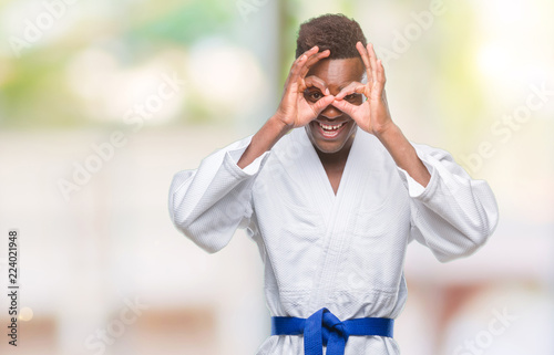 Young african american man over isolated background wearing kimono doing ok gesture like binoculars sticking tongue out, eyes looking through fingers. Crazy expression.