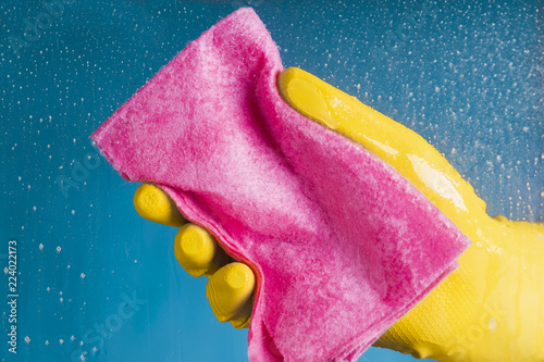 Obraz na plátne Hand in a yellow glove holding a dishcloth - washing the glass