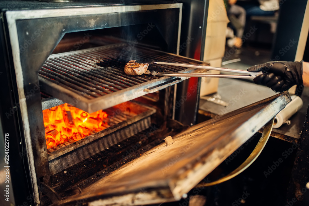 Chef preparing a steak on the grill oven