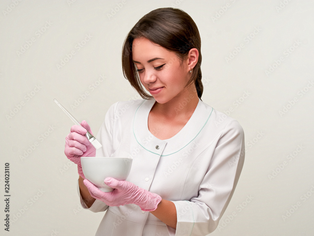 Healthcare concept. Doctor cosmetologist preparing and making mask procedures. Mask beautifing a face skin. Cosmetic means and skin cream. Cosmetologist works in a beauty salon on white background Healthcare concept. Doctor cosmetologist preparing and making mask procedures. Mask beautifing a face skin. Cosmetic means and skin cream. Cosmetologist works in a beauty salon on white background