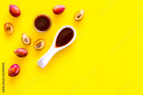 Fresh tkemali sauce. Traditional caucasian, georgian sauce or plum jam in spoon near plums on yellow background top view copy space