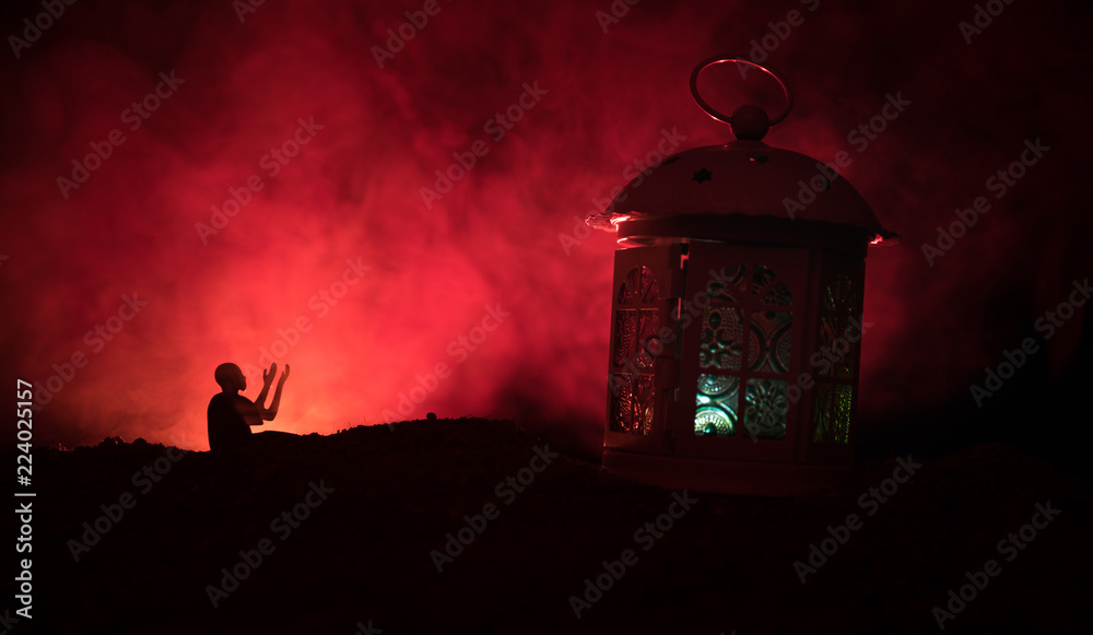 Ornamental Arabic lantern with burning candle glowing at night on dark toned foggy background. Festive greeting card, invitation for Muslim holy month Ramadan Kareem.