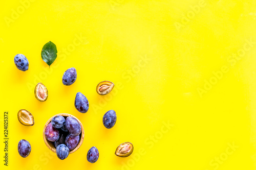 Blue plum for dessert. Purple plum and leaves pattern on yellow background top view copy space