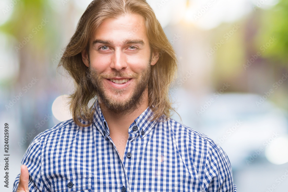 Young handsome man with long hair over isolated background doing happy thumbs up gesture with hand. Approving expression looking at the camera with showing success. Young handsome man with long hair over isolated background doing happy thumbs up gesture with hand. Approving expression looking at the camera with showing success.
