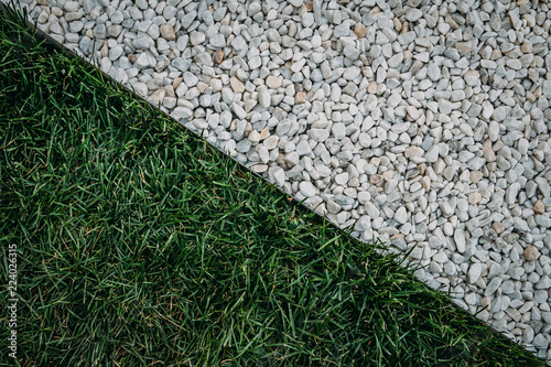 Abstract diagonal composition with green grass field and white stones surface texture, top view photo