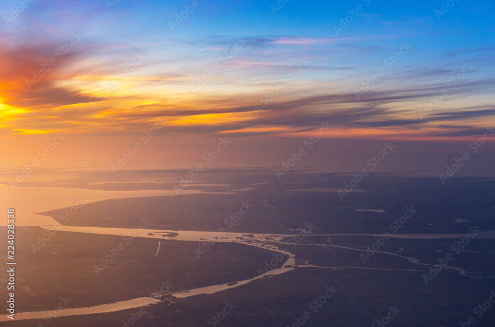 beautiful sunset with aerial view of sea and river from airplane, plane, window seat over Netherlands, Europe