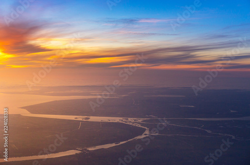 beautiful sunset with aerial view of sea and river from airplane, plane, window seat over Netherlands, Europe