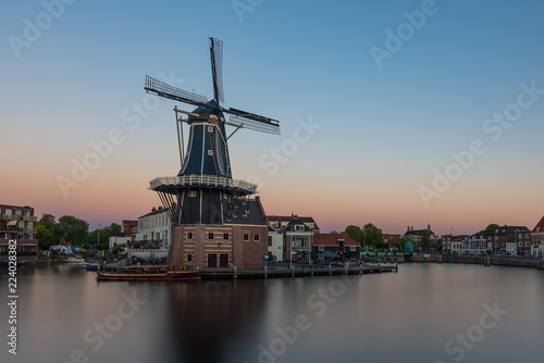 Dutch windmill, in the town of Haarlem, at sunset. The water is smooth, due to a long shutter speed - room for copy