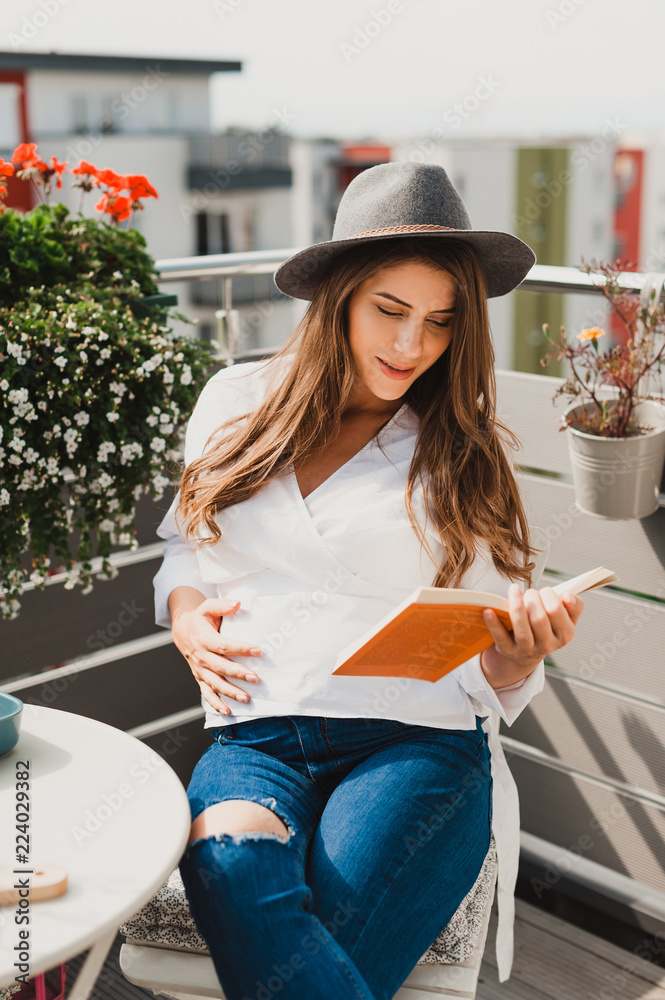 Φωτογραφία Beautiful young pregnant hipster girl, sitting relaxed on the terrace holding a