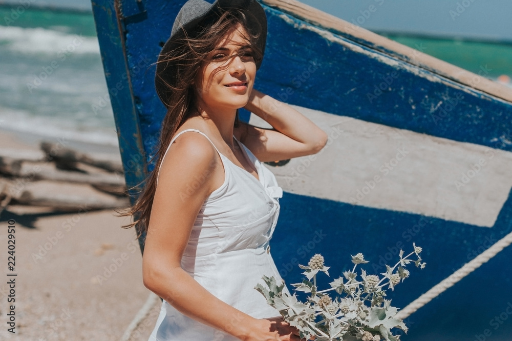 Φωτογραφία Beautiful young hipster girl enjoying a sunny beautiful day walking along the beach picking wild plants and looking happy