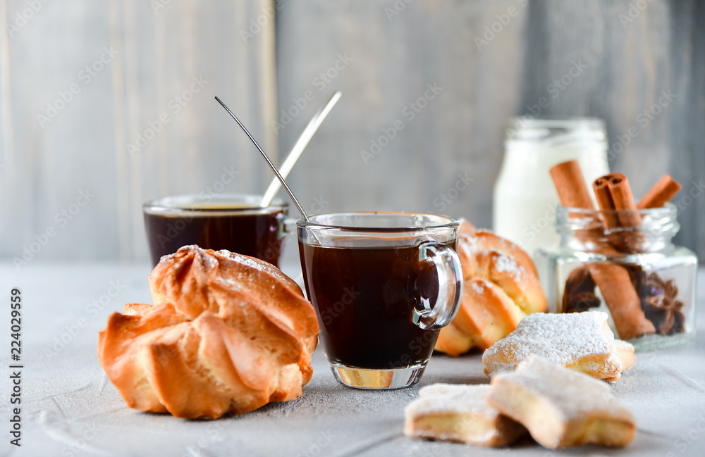 two cups of black coffee in transparent cups, milk and round eclairs with cream filling two cups of black coffee in transparent cups, milk and round eclairs with cream filling