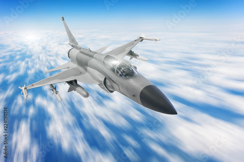 Military fighter aircraft at high speed, flying high in blue sky.