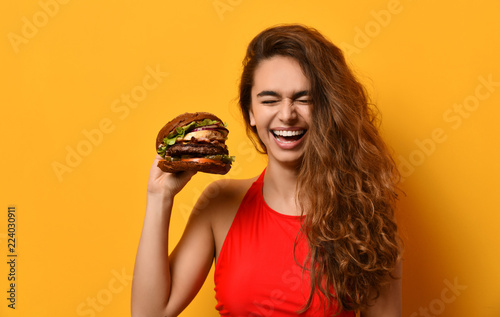 Obraz na płótnie Woman hold big barbecue burger sandwich with hungry mouth happy screaming laughing on yellow background w salonie