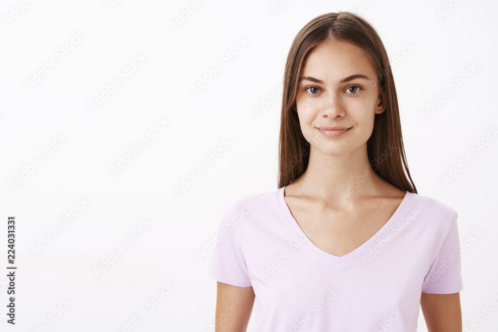 Friendly charming caucasian female brunetee with long hair and clean healthy skin smiling with polite and cute expression feeling confident in own powers while participating in competition Friendly charming caucasian female brunetee with long hair and clean healthy skin smiling with polite and cute expression feeling confident in own powers while participating in competition