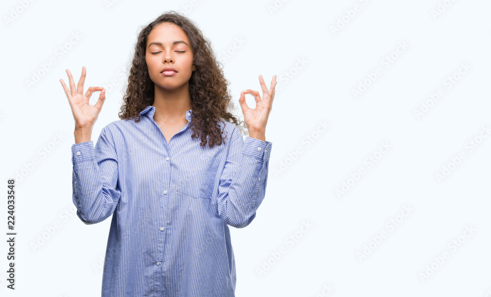 Young hispanic business woman relax and smiling with eyes closed doing meditation gesture with fingers. Yoga concept. Young hispanic business woman relax and smiling with eyes closed doing meditation gesture with fingers. Yoga concept.