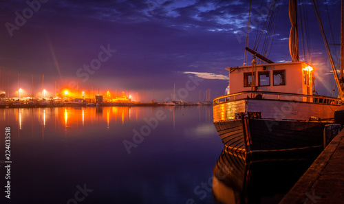 Heavy clouds above Tallinn, Pirita. Night illumination, reflections boat moored at the small marina of Estonia.
