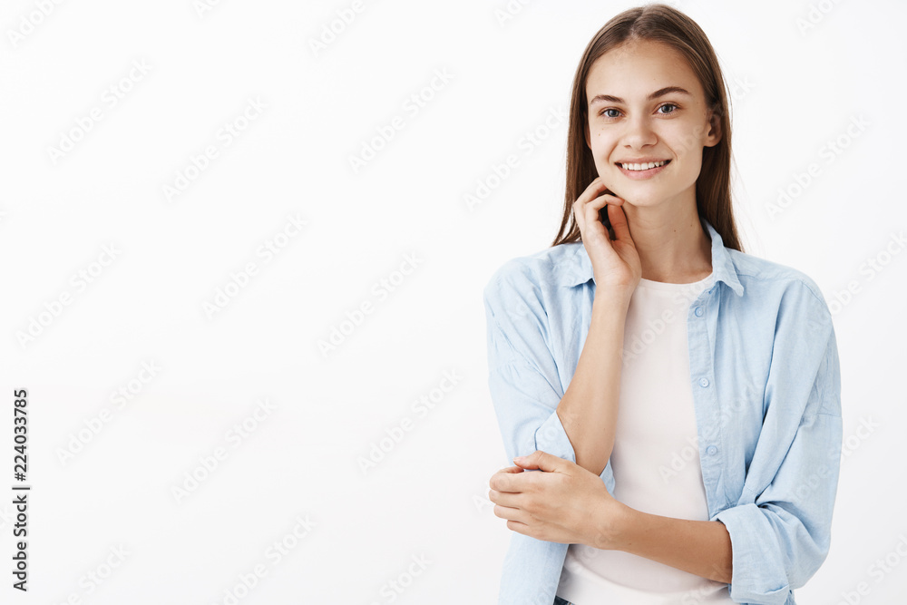 Girl having big dreams entering university to fulfill it. Portrait of hopeful tender and feminine european female brunette in blue blouse over white t-shirt touching face gently and smiling at camera Girl having big dreams entering university to fulfill it. Portrait of hopeful tender and feminine european female brunette in blue blouse over white t-shirt touching face gently and smiling at camera