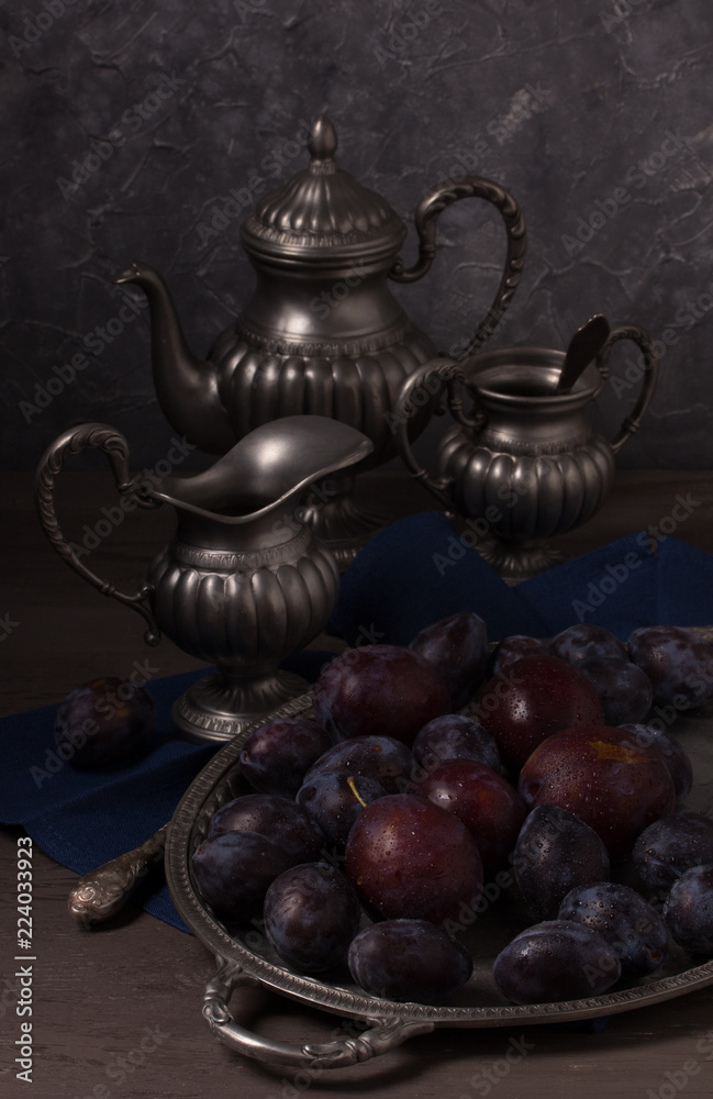 Still life with fresh plums and antique dishes