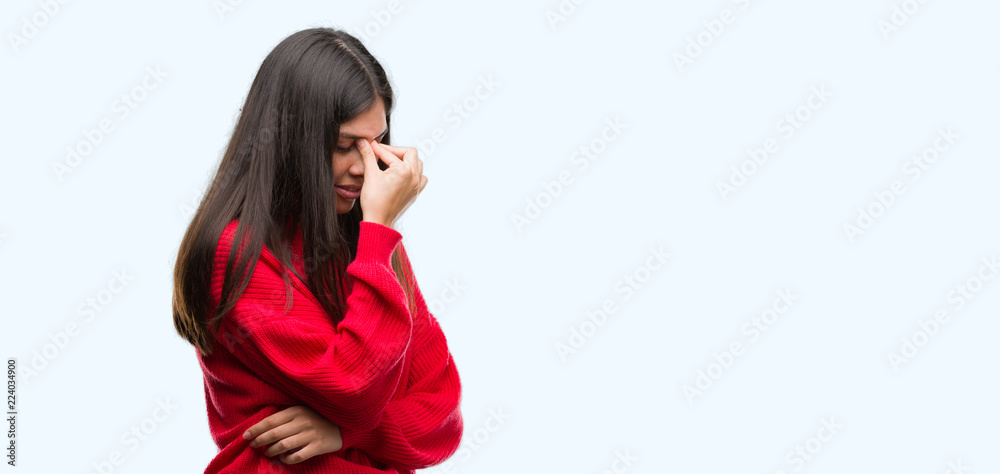Young beautiful hispanic wearing red sweater tired rubbing nose and eyes feeling fatigue and headache. Stress and frustration concept.