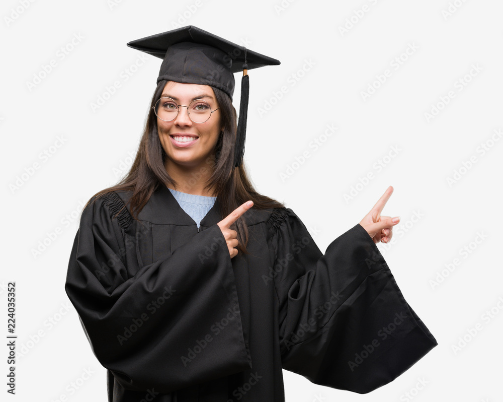 Young hispanic woman wearing graduated cap and uniform smiling and looking at the camera pointing with two hands and fingers to the side. Young hispanic woman wearing graduated cap and uniform smiling and looking at the camera pointing with two hands and fingers to the side.