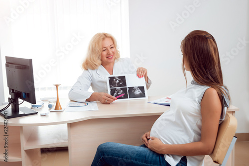 Doctor gynecologist consulting pregnant woman. Patient at doctor office. Pregnant woman at hospital. © romaset