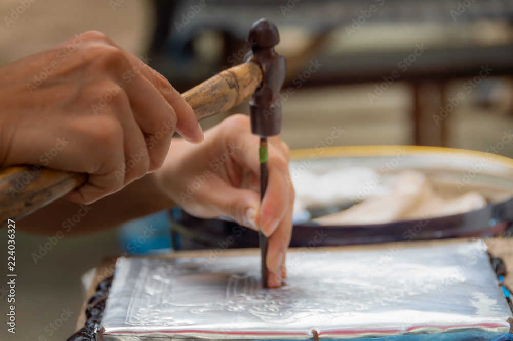 Obraz premium The artisans are using hammers and steel Engraved gorgeus pattern on silver plate To handcraft concept.