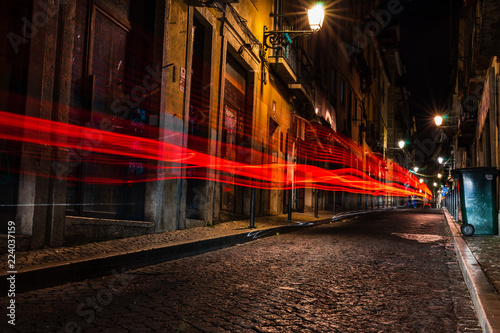 The amazing city of Lisbon, Portugal at night. Red tail light trails on the narrow streets of Bario Alto in Lisbon.