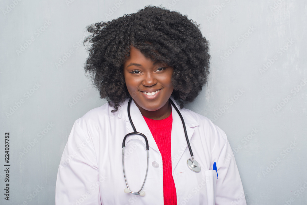 Young african american doctor woman over grey grunge wall with a happy and cool smile on face. Lucky person. Young african american doctor woman over grey grunge wall with a happy and cool smile on face. Lucky person.