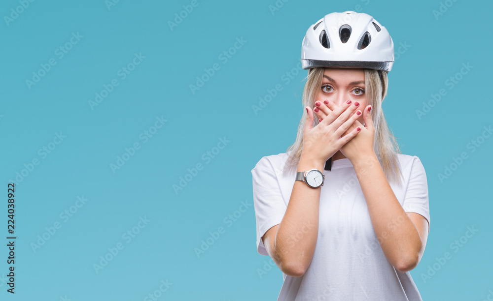 Young blonde woman wearing cyclist security helmet over isolated background shocked covering mouth with hands for mistake. Secret concept. Young blonde woman wearing cyclist security helmet over isolated background shocked covering mouth with hands for mistake. Secret concept.