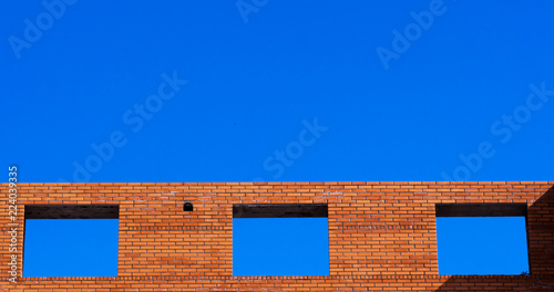 Photos Blue sky visible through the window's holes frames in red brick wall