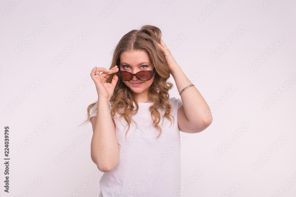 Portrait of enigmatic beautiful white girl fixing hair wearing sunglasses on white background Portrait of enigmatic beautiful white girl fixing hair wearing sunglasses on white background