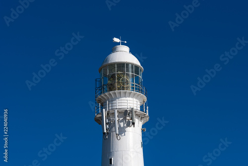 Close up of a lighthouse against a blue sky.