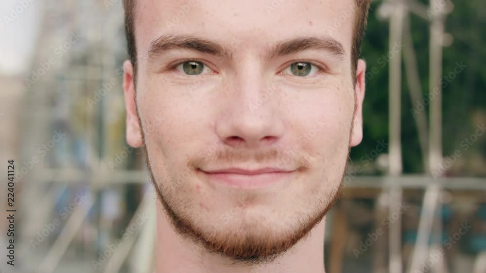 A young red-haired man with a beard smiling in the city street. Close-up shot. Soft focus A young red-haired man with a beard smiling in the city street. Close-up shot. Soft focus