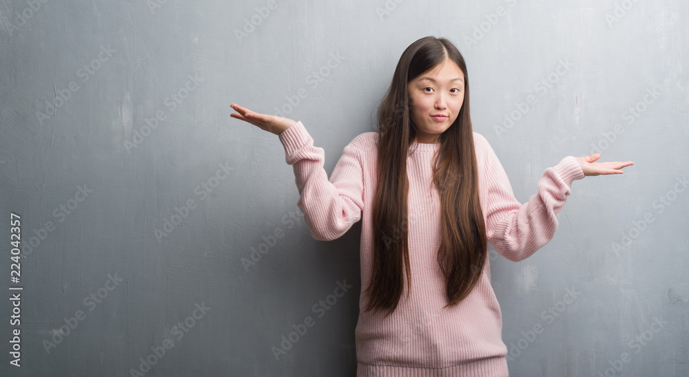 Young Chinese woman over grey wall clueless and confused expression with arms and hands raised. Doubt concept. Young Chinese woman over grey wall clueless and confused expression with arms and hands raised. Doubt concept.