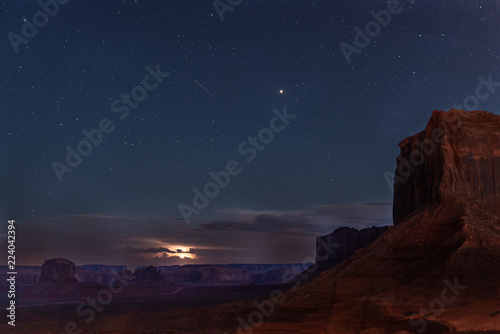 Dramatic Monument Valley night scene with starry skies and thunderstorms