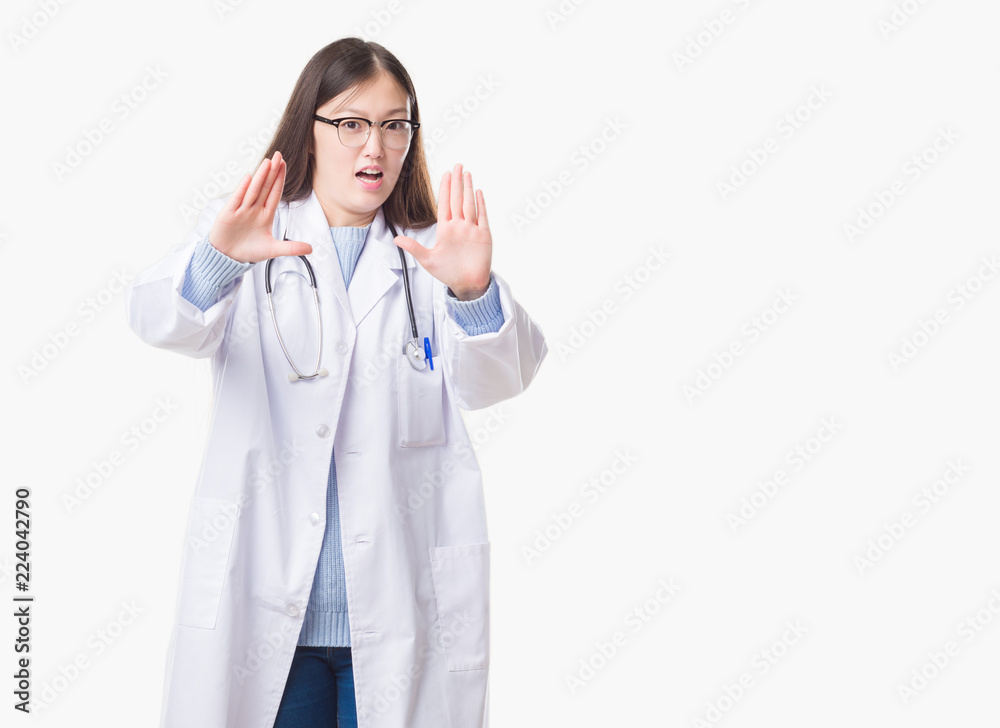 Young Chinese doctor woman over isolated background afraid and terrified with fear expression stop gesture with hands, shouting in shock. Panic concept. Young Chinese doctor woman over isolated background afraid and terrified with fear expression stop gesture with hands, shouting in shock. Panic concept.