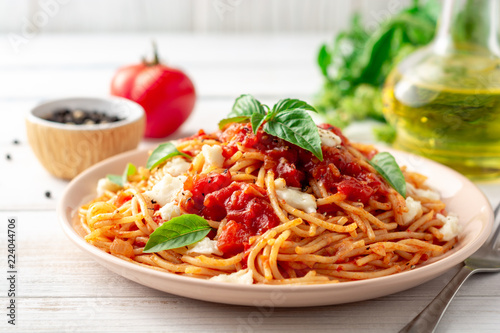 Fototapet Spaghetti pasta with tomato sauce, mozzarella cheese and fresh basil in plate on white wooden background