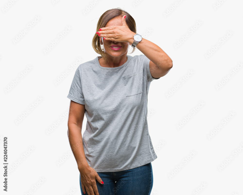 Fototapeta premium Middle age senior hispanic woman wearing glasses over isolated background smiling and laughing with hand on face covering eyes for surprise. Blind concept.