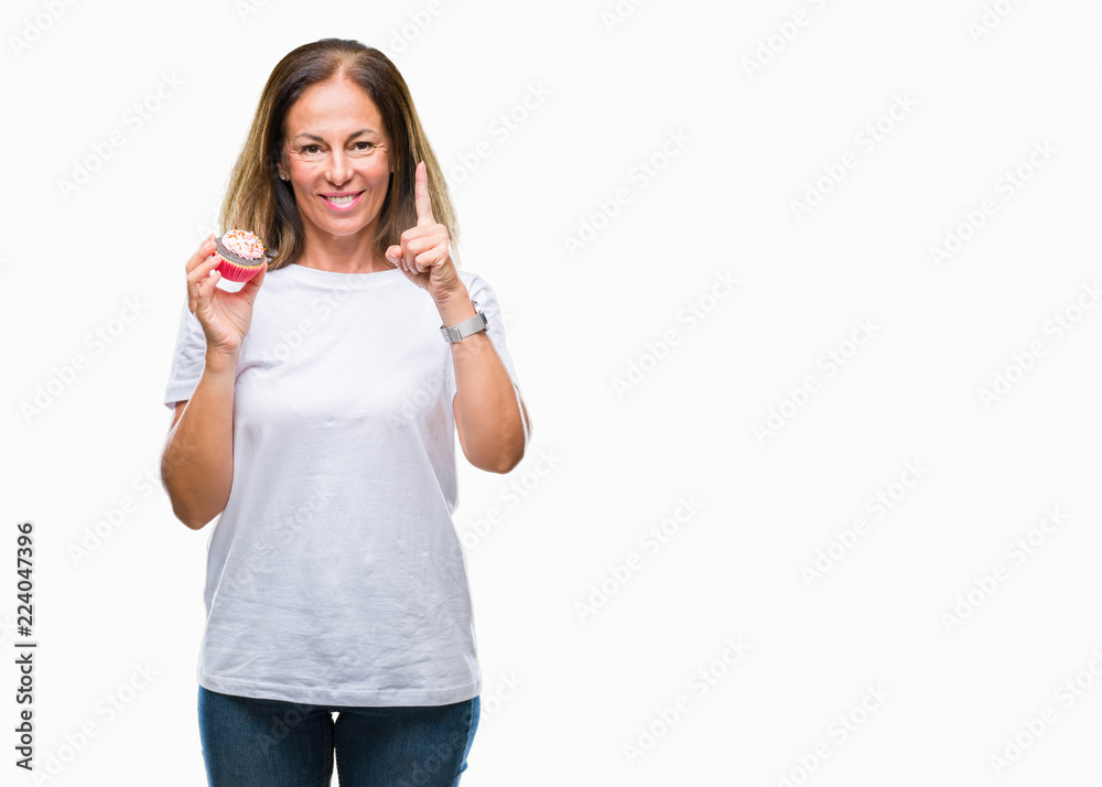 Middle age hispanic woman eating cupcake over isolated background surprised with an idea or question pointing finger with happy face, number one Middle age hispanic woman eating cupcake over isolated background surprised with an idea or question pointing finger with happy face, number one