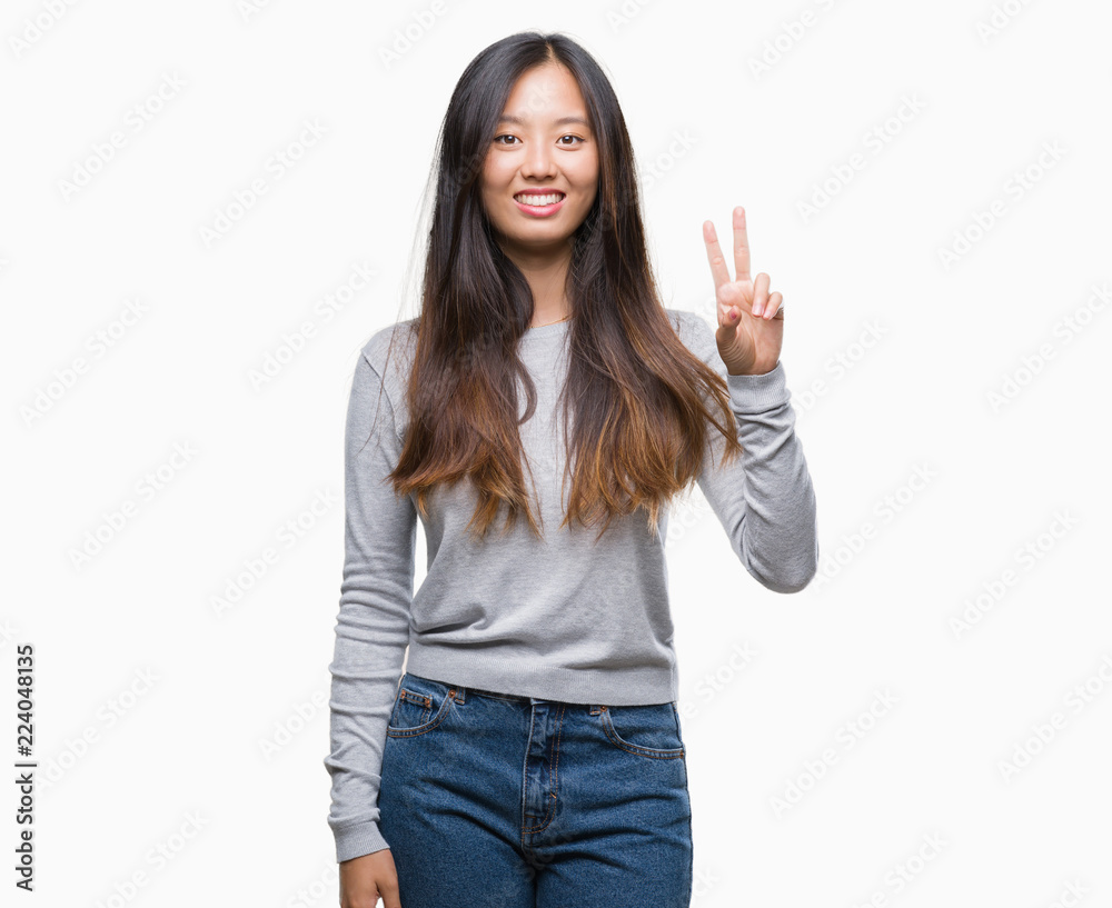 Young asian woman over isolated background smiling with happy face winking at the camera doing victory sign. Number two. Young asian woman over isolated background smiling with happy face winking at the camera doing victory sign. Number two.