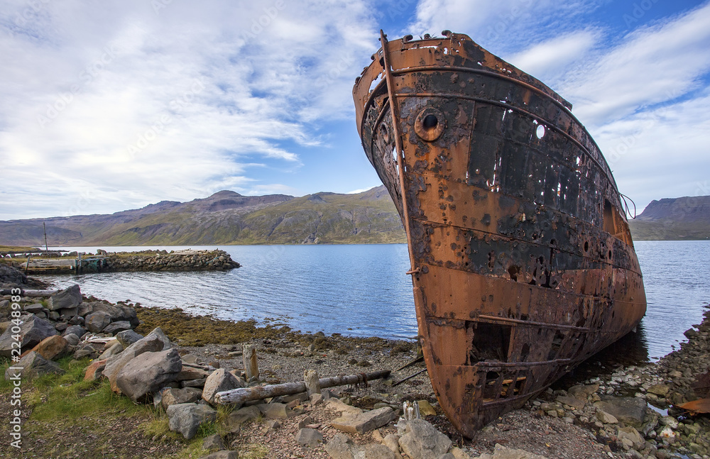 Rusted hull of a steel shipwreck located on the shore of Djúpavík, Iceland.