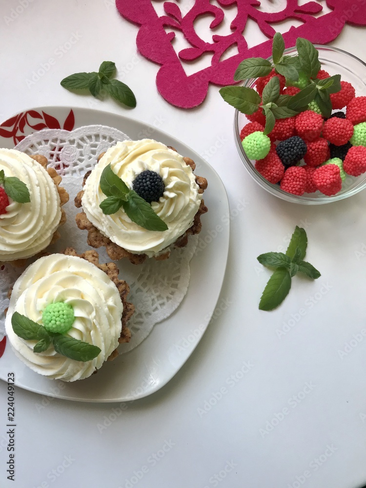 A cake basket with cream and berries and mint leaves. Nearby is a container with berries of different colors for decoration. A cake basket with cream and berries and mint leaves. Nearby is a container with berries of different colors for decoration.
