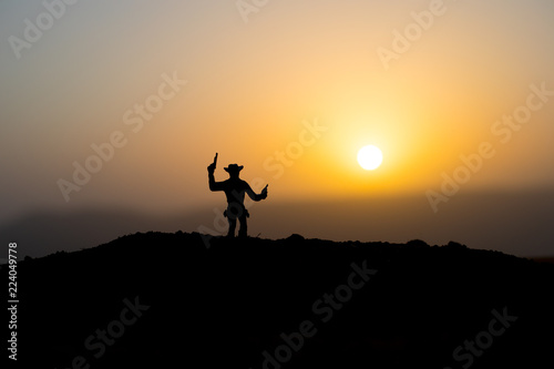 Cowboy concept. Silhouette of Cowboys at sunset time. A cowboy silhouette on a mountain with an yellow sky.