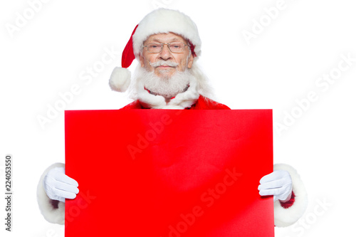 Christmas. The kind Santa Claus in white gloves holds an empty cardboard of red color. Place for advertising, for text, empty space. Copy-paste. Isolated on white background.