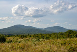 Maine view of mountains in the distance with puffy clouds hovering over